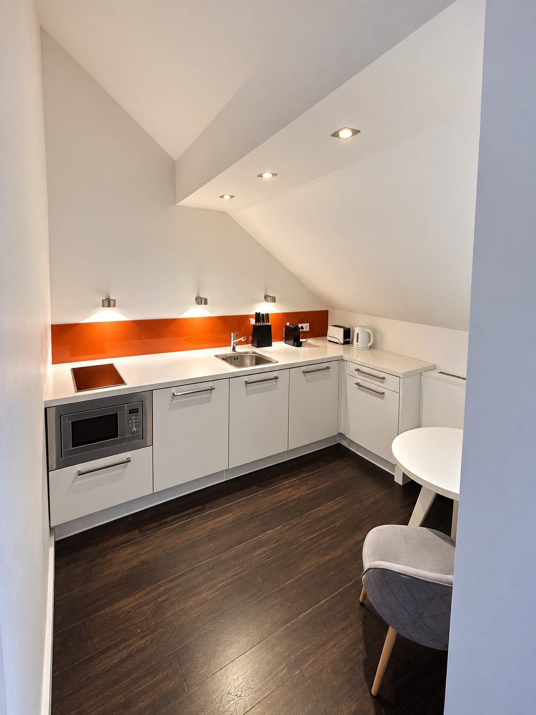 Dachgeschoss-Apartment: Küchenzeile mit Esstisch unter der Dachschräge
