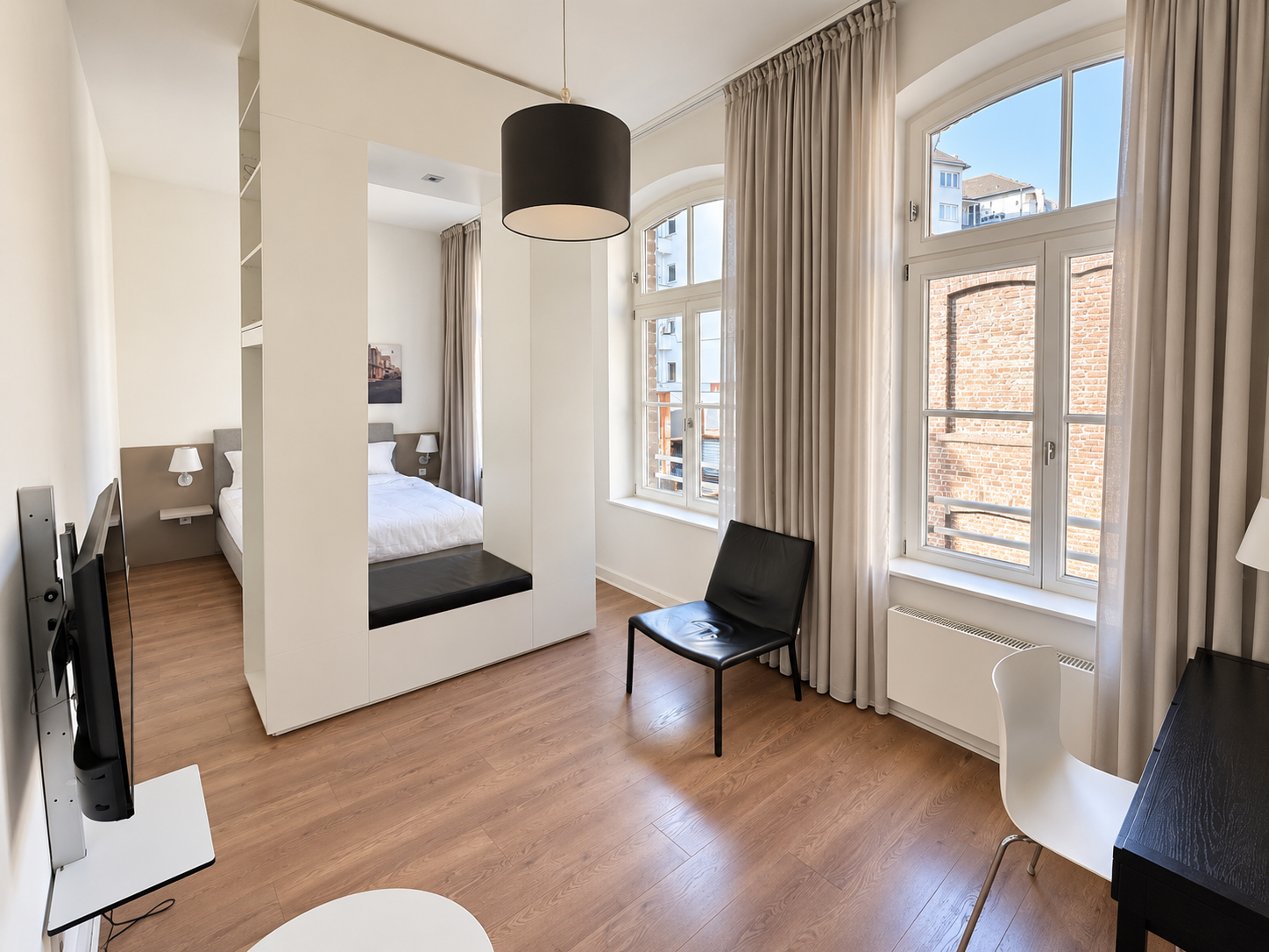Apartment XS im Anbau: heller Wohnbereich mit Fenstern, Sitzplatz und abgetrenntem Schlafbereich